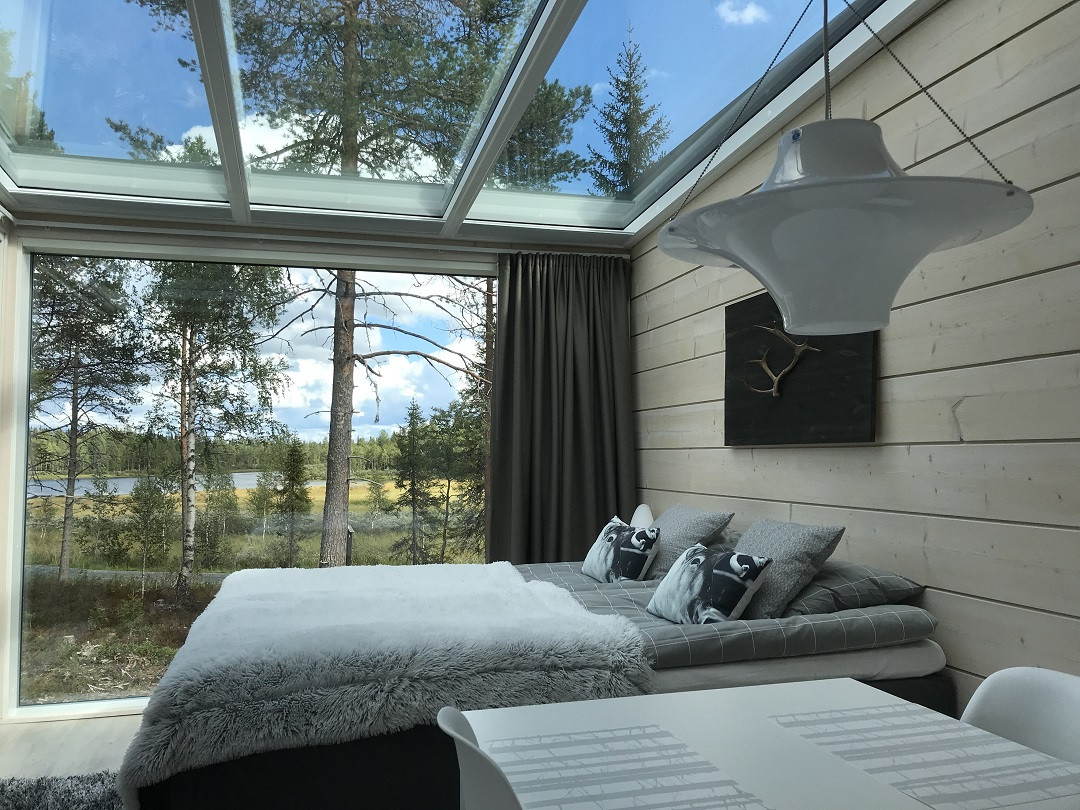 Lasikattoinen mökki kesämaisemalla Iisakki Villagessa.