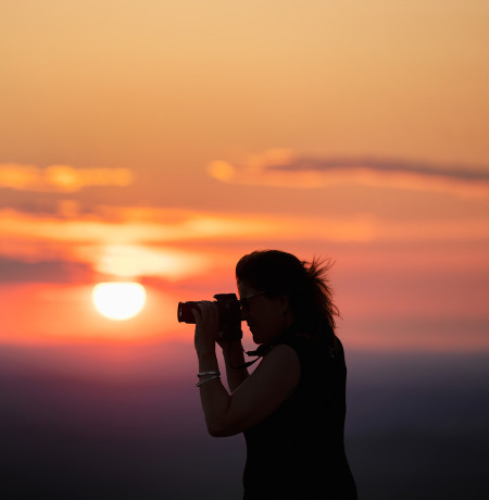 Nainen kuvaa kameralla auringonlaskussa