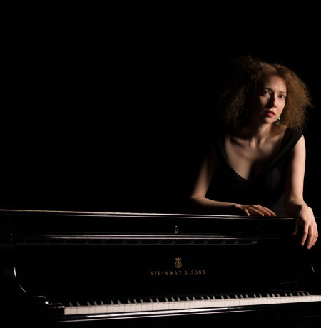 Kuvassa pianisti Irina Zahharenkova nojaamassa Steinway flyygeliin