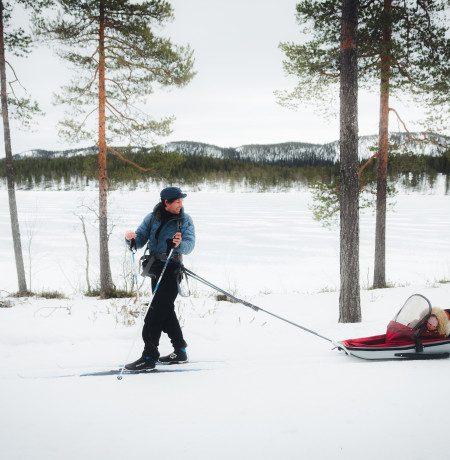 Maastohiihtäjä ladulla, lapsi mukana ahkiossa. Kuva Mikko Santasalo
