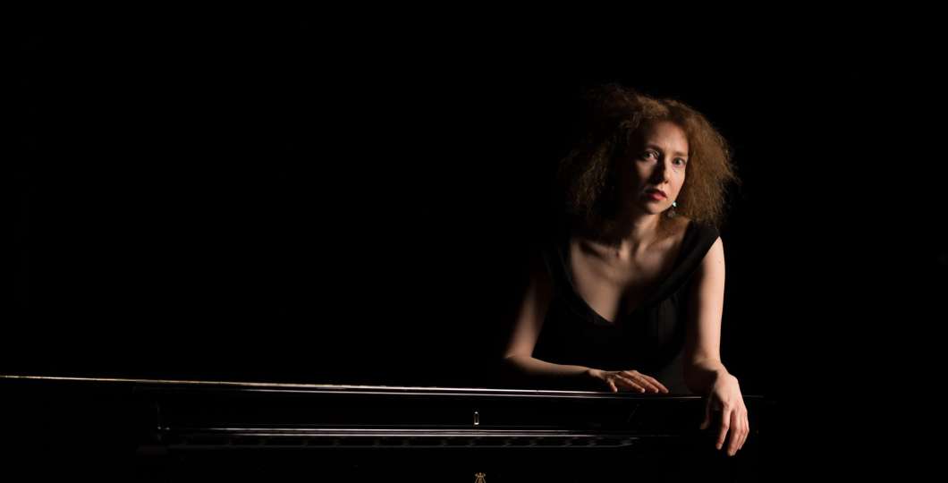 Kuvassa pianisti Irina Zahharenkova nojaamassa Steinway flyygeliin