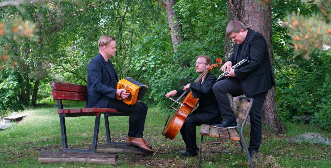 Kuvassa yhtye Tango del norte istuu soitinten kanssa kesäisten puiden alla.